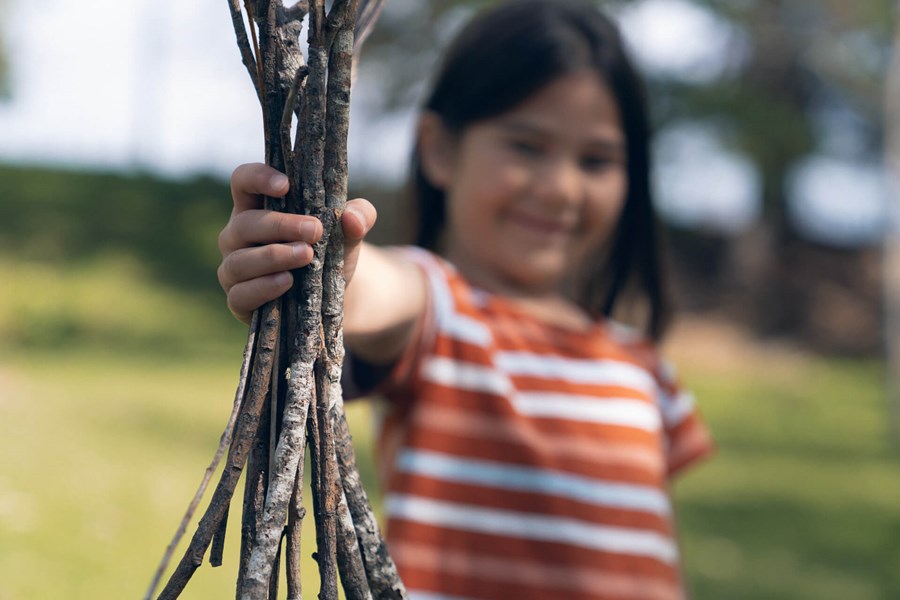 young girl holding a bundle of tree branches