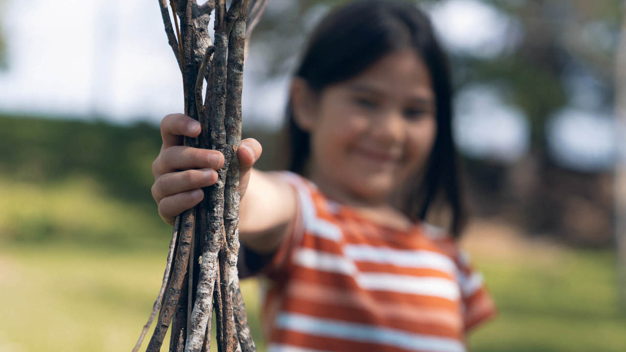 young girl holding a bundle of tree branches