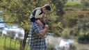 young dad holding son on his shoulders in the park