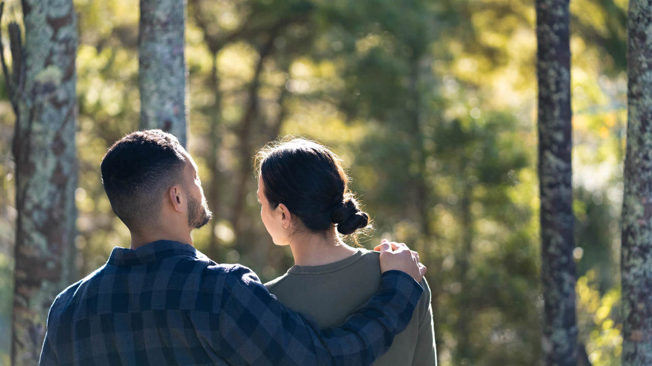 young couple holding each other in the forest - back view