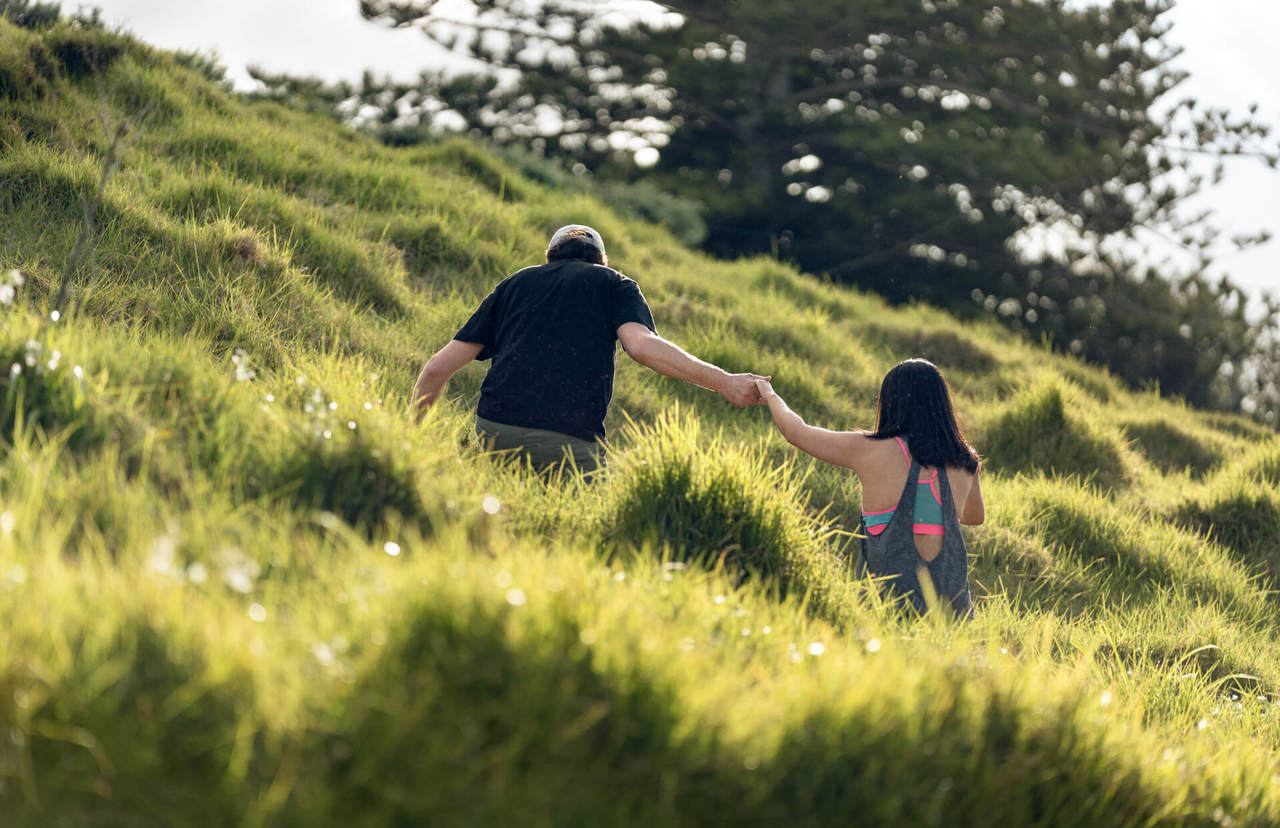 young couple holding hands in the park - back view