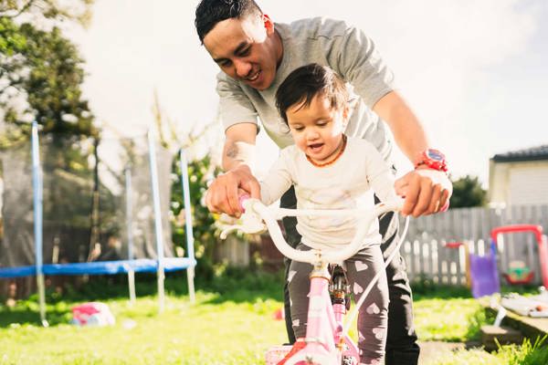 Dad helping daughter ride a bike
