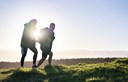 young couple walking in park with sun in background