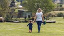 young mum and daughter walking in the park - back view