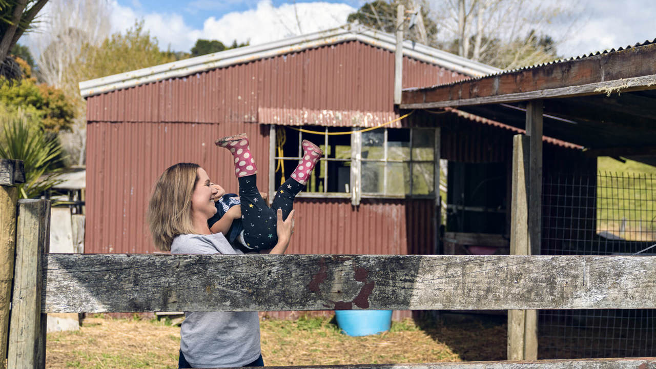 young mum playing with daughter - house in background