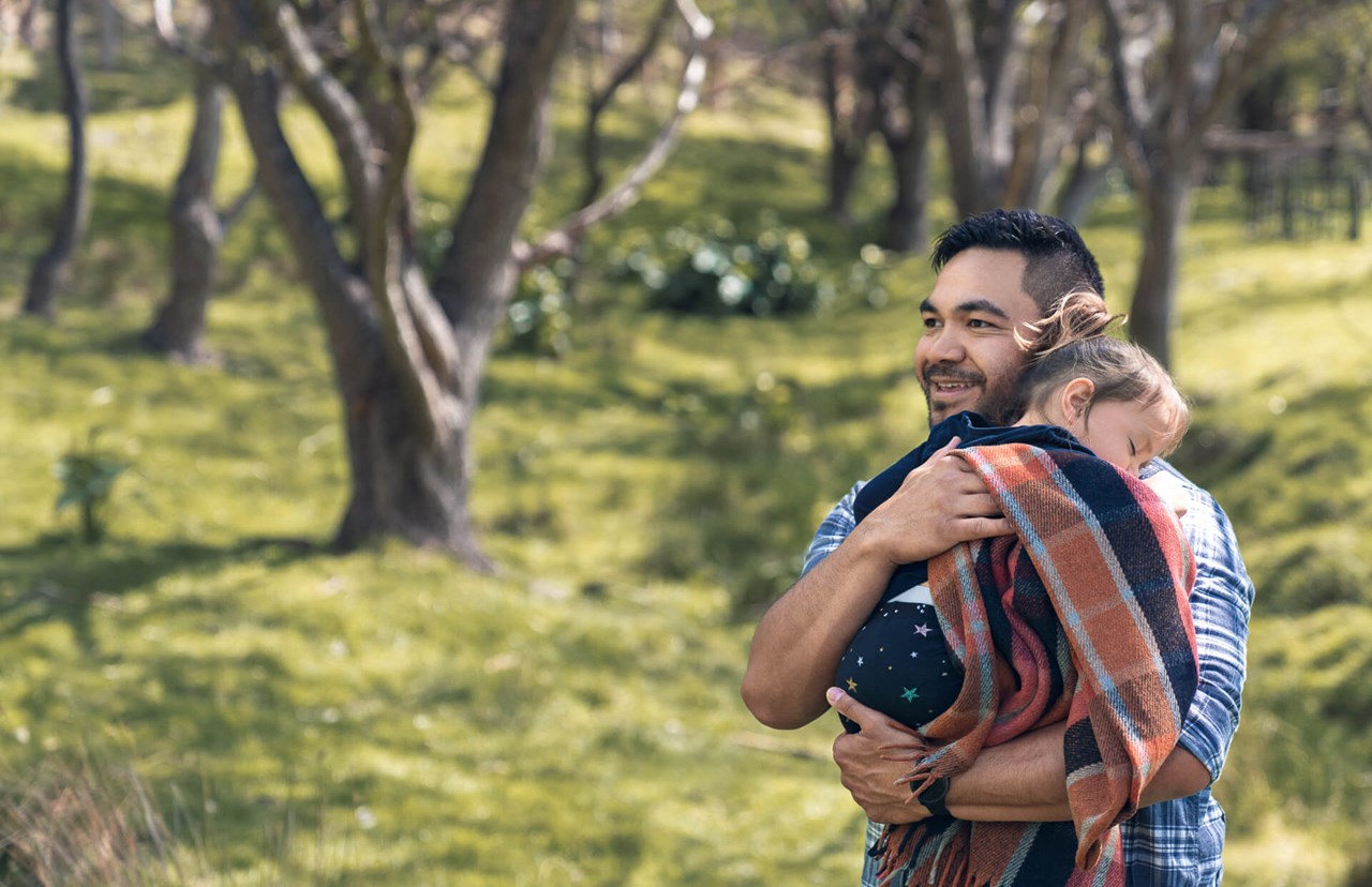 young dad holding sleeping daughter in the park young dad holding sleeping daughter in the park