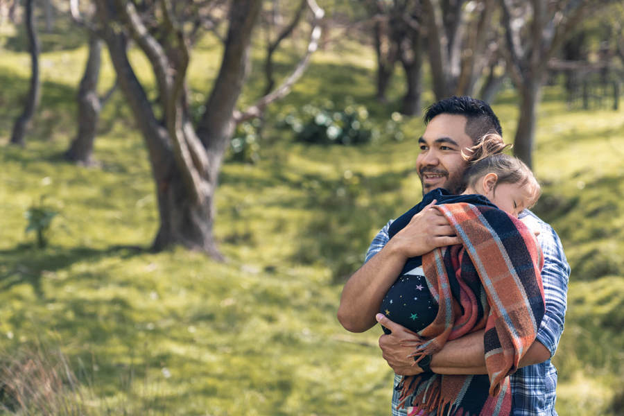 young dad holding sleeping daughter in the park Westpac life insurance is powered by Fidelity Life.