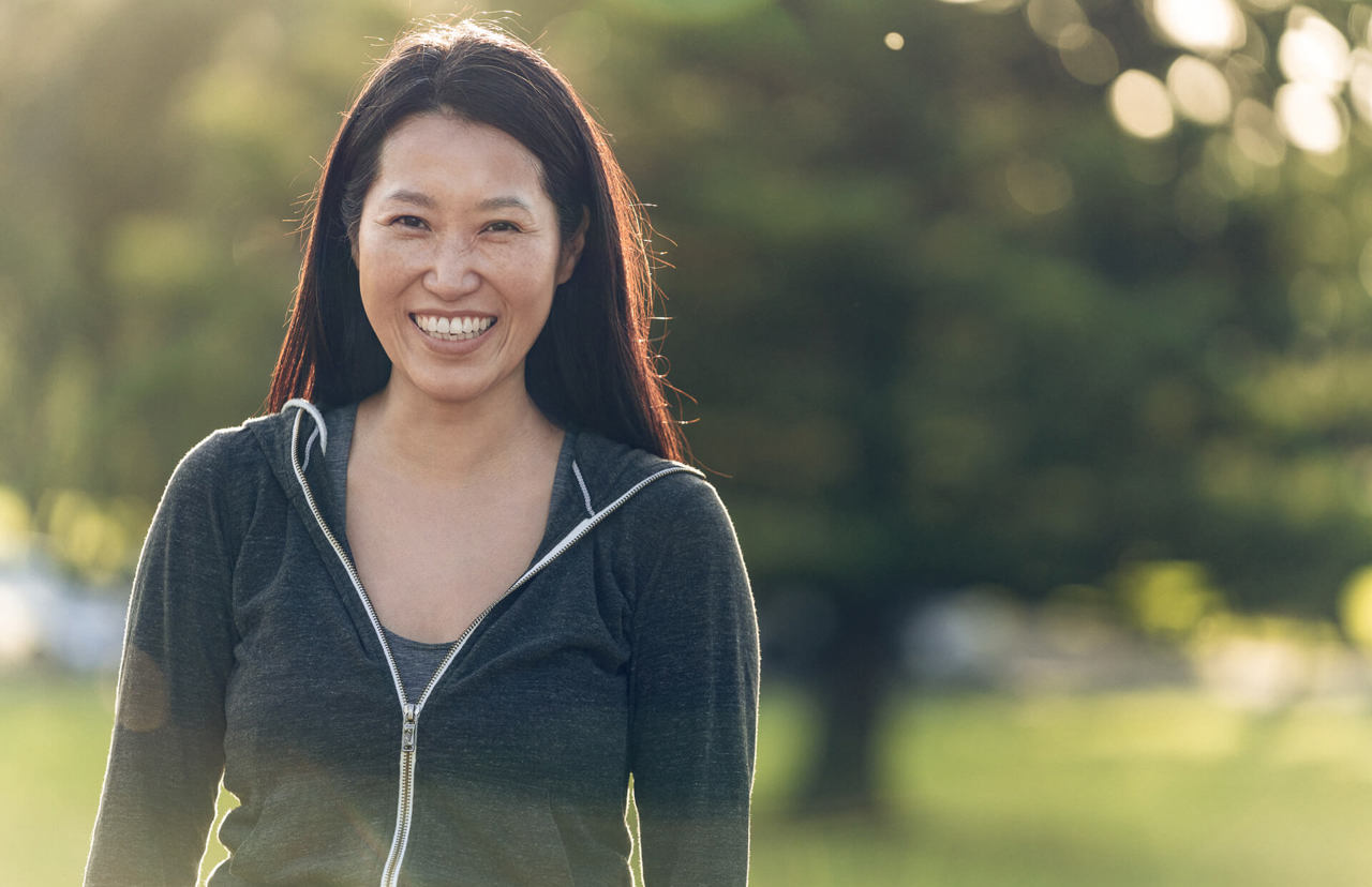 smiling asian girl in the park - front view